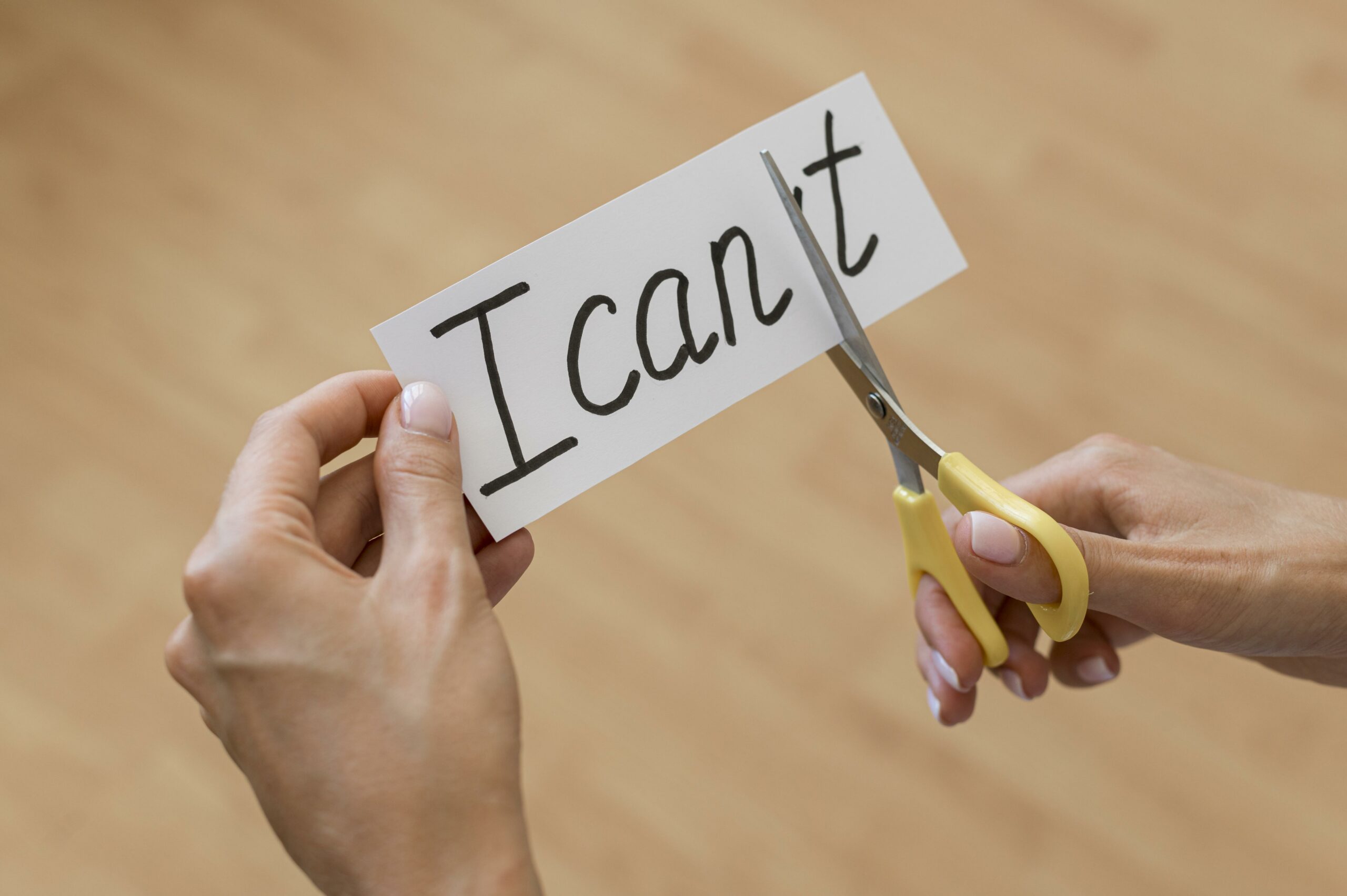 ciseaux coupant une étiquette entre le I can et le T